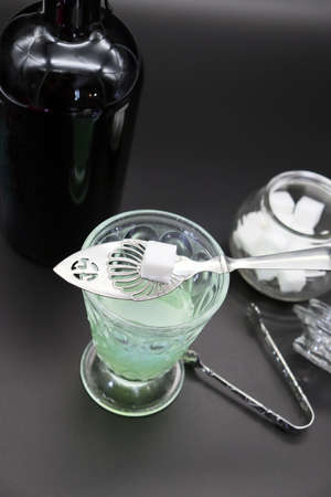 Absinthe with a spoon and sugar cube in an old scratched glassの写真素材