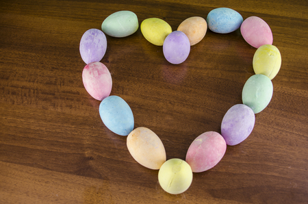 easter eggs in the shape of a heart, horizontal with brown wood background