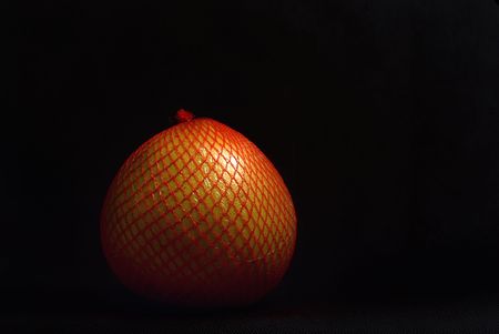 Pomelo fruit packed in a plastic net on a black background