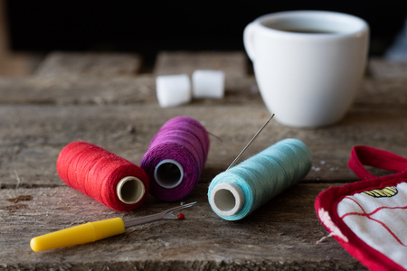 needle and thread on an old table plus coffee