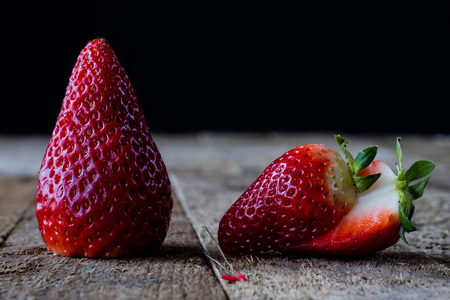 Strawberries and tangerines on an old wooden table in an old kitchen, black backgroundの写真素材