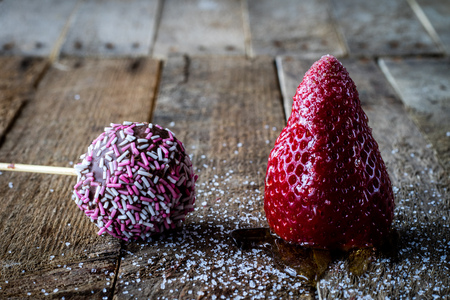 Mandarin, strawberry and chocolate on an old wooden table in an old kitchen on a black backgroundの写真素材
