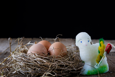 Eggs in a nest with a sack on an old wooden table, black backgroundの写真素材