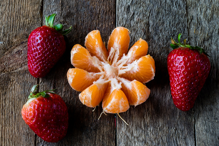 Strawberries and tangerines on an old wooden table in an old kitchen, black backgroundの写真素材