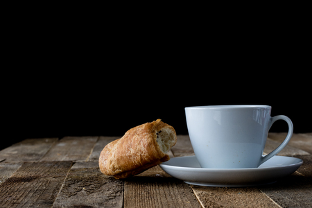 Coffee in a cup with a sweet dessert on an old table, black backgroundの写真素材