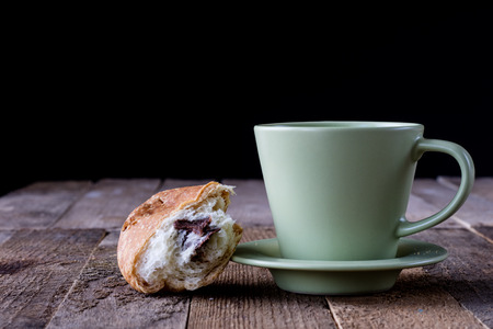 Coffee in a cup with a sweet dessert on an old table, black backgroundの写真素材