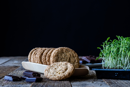 Milk and chocolate cookies on an old wooden table, black backgroundの写真素材