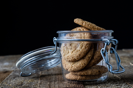Milk and chocolate cookies on an old wooden table, black backgroundの写真素材