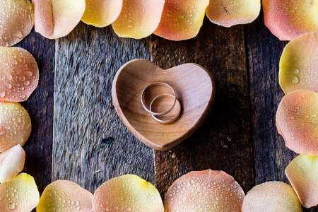 Wedding rings in rose petals on a wooden tableの写真素材
