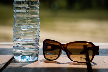 Water bottle and sunglasses on the table on a sunny day.の写真素材