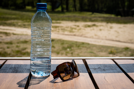 Water bottle and sunglasses on the table on a sunny day.の写真素材