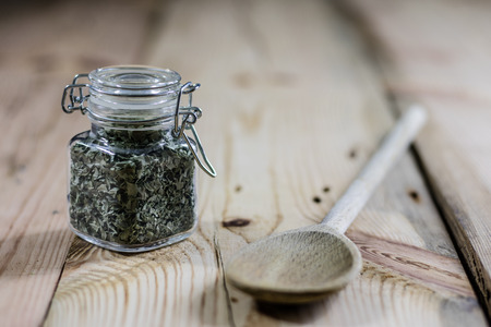 Spice in a jar on a wooden table, wooden spoon, black backgroundの写真素材