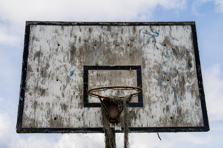 Old basketball court, basket, snatched netting against the sky and cloudsの写真素材