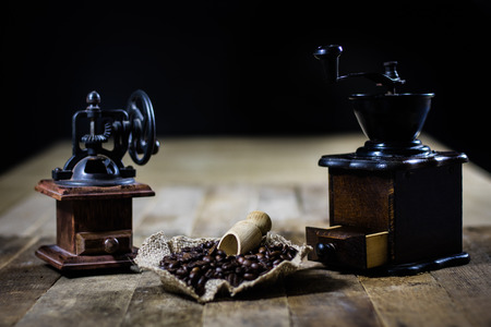 Old stylish grinder for grinding tasty coffee on an old wooden table, black backgroundの写真素材