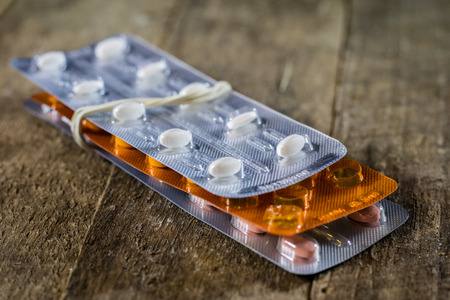 Medical tablets on a wooden table. White pills in plastic containers. Wooden table, black background.の写真素材