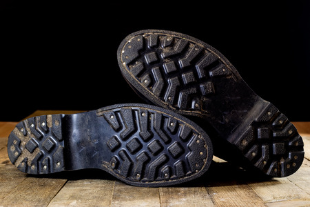 Old black Polish military boots on a wooden table. Black background.の写真素材
