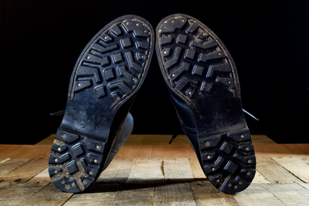 Old black Polish military boots on a wooden table. Black background.の写真素材