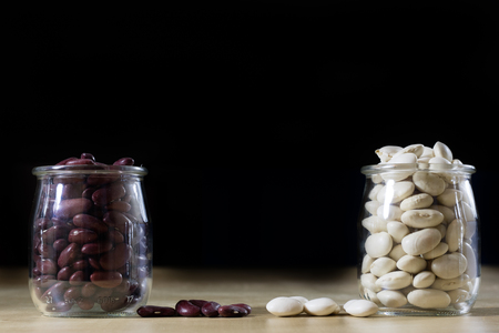 Delicious bean in a glass jar on a wooden kitchen table. Black background.の写真素材