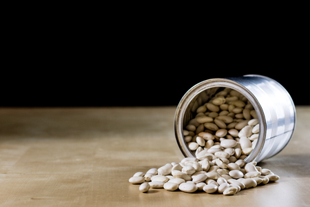 Delicious beans in a metal jar on a wooden kitchen table. Black background.の写真素材