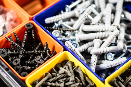 Screws segregated in plastic colored containers. Box for builder and DIY. Black background.の写真素材