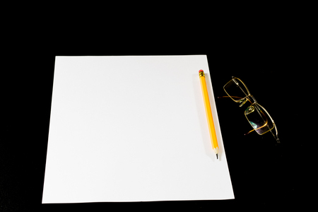 White card on black table. Glasses and pencil. Place to make notes. Black backgroundの写真素材