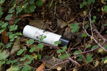 Plastic trash in the forest. Tucked nature. Plastic container lying in the grass. Season of autumn.