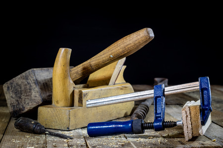 Old good carpentry, tools drill bit. Wooden carpentry table and old good carpentry tools on it. Black background.の写真素材