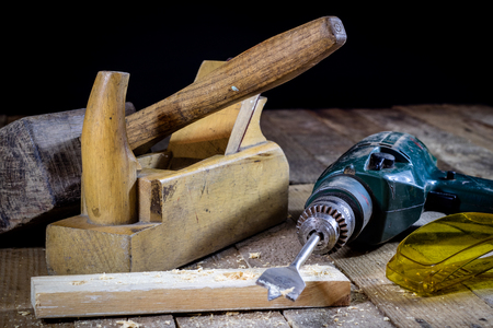 Old good carpentry, tools drill bit. Wooden carpentry table and old good carpentry tools on it. Black background.の写真素材