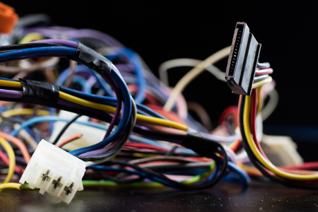 Old entangled cables, electronics and old cable connectors on a black table. Black backgroundの写真素材