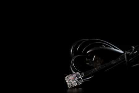 Old entangled cables, electronics and old cable connectors on a black table. Black backgroundの写真素材