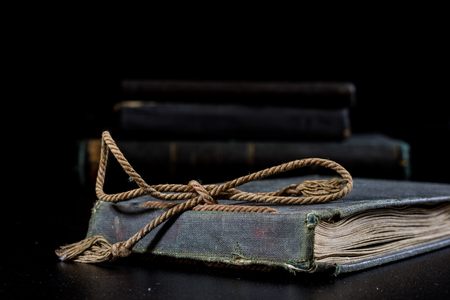 An old book lying on a black table. In the background a pile of old chunks. Black table, black background.の写真素材