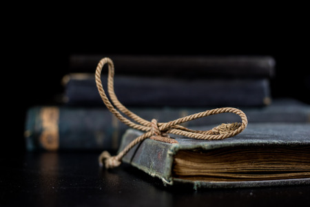 An old book lying on a black table. In the background a pile of old chunks. Black table, black background.の写真素材
