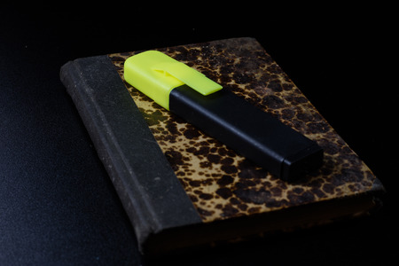 Old book lying on a black countertop and office marker. black backgroundの写真素材