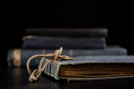 An old book lying on a black table. In the background a pile of old chunks. Black table, black background.の写真素材