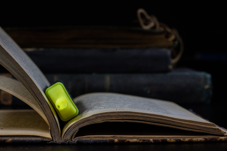 Old book lying on a black countertop and office marker. black backgroundの写真素材