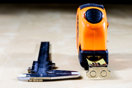 Measure to measure distance. A measure lying on a wooden table. Black backgroundの写真素材