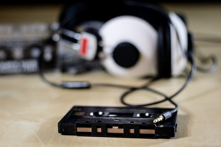 Cassette tape and headphones for listening to music. Old good music from the 80s. Wooden table, black backgroundの写真素材