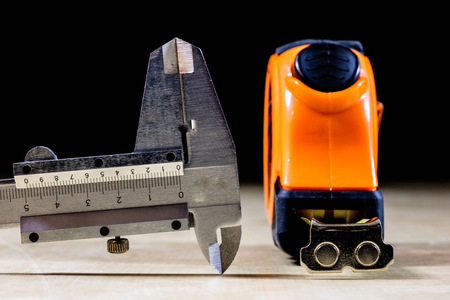 Measure to measure distance. A measure lying on a wooden table. Black backgroundの写真素材