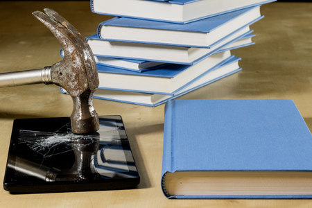 Heap of books reading on a wooden table. Beside lies and tablet. Black background.の写真素材