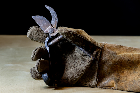 Hand in glove with tool for work in workshop. Hand protected by working coat. Workshop tool. Black background.の写真素材