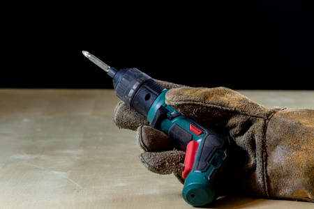 Hand in glove with tool for work in workshop. Hand protected by working coat. Workshop tool. Black background.の写真素材
