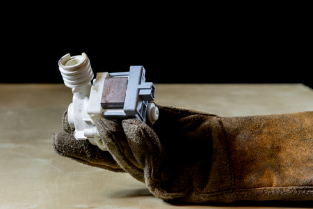Hand in glove with tool for work in workshop. Hand protected by working coat. Workshop tool. Black background.の写真素材