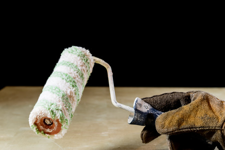 Hand in glove with tool for work in workshop. Hand protected by working coat. Workshop tool. Black background.の写真素材