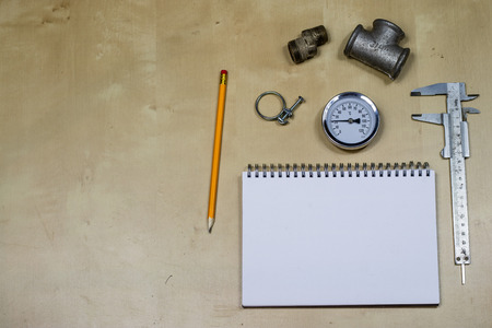 Materials, accessory and spare parts for hydraulics. Notes and measuring tools on the workshop table. Wooden table.の写真素材