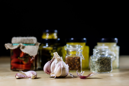 Fresh garlic smelling on the kitchen table. Mortar and kitchenware. Wooden table, black backgroundの写真素材