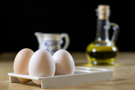 Egg, olive oil, spices on the kitchen table. Wooden table, kitchen, black background.の写真素材