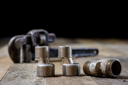 Hydraulics, tools for plumber on wooden table. Workshop, table and tools - adjustable spanner, connectors, keys. Black backgroundの写真素材