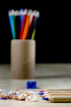 crayons and pencil sharpener on a wooden office table. Crayons with sharpening crayons and pencils on the table next to colored pencils. black background.の写真素材