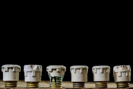 Old ceramic fuse holders. Old electrical accessories. Wooden table, black backgroundの写真素材