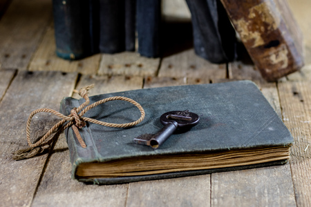 Very old book and key on an old wooden table. Old room, wooden table and book with key, black backgroundの写真素材